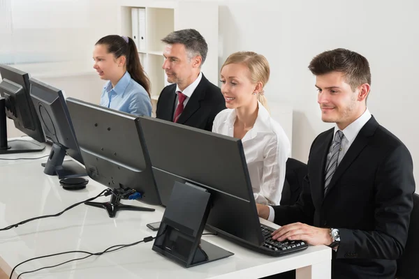 Empresários digitando em computadores desktop — Fotografia de Stock