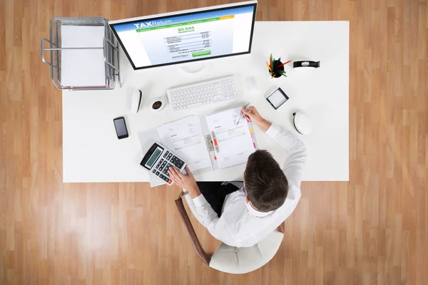 Uomo d'affari Calcolo delle tasse di fronte al computer — Foto Stock