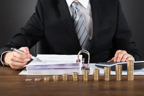 Empresário calculando fatura com moedas na mesa — Fotografia de Stock