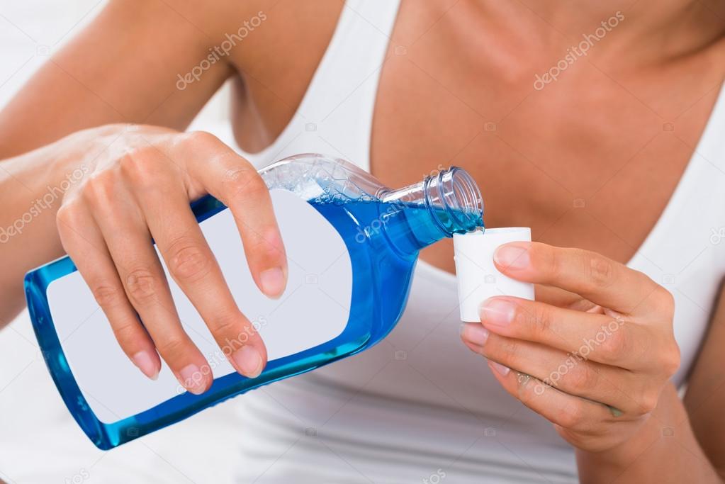 Woman Pouring Mouthwash Into Bottle Cap