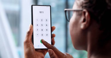 Afrika kökenli Amerikalı Kadın, arka planda akıllı telefondan 911 'i arıyor.