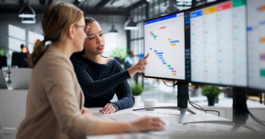 Gantt Çizelgesini Ofisteki bilgisayar ekranında analiz eden genç İspanyol kadın. Kariyer Olasılıkları Ofis Yöneticisini de içerir