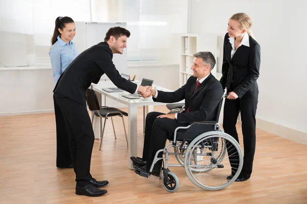 Homme d'affaires en fauteuil roulant serrant la main d'un collègue — Photo