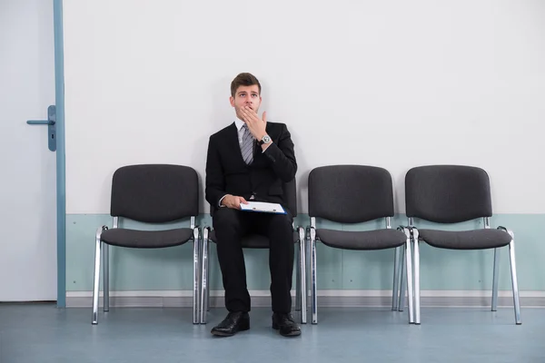 Empresário bocejando enquanto sentado na cadeira — Fotografia de Stock