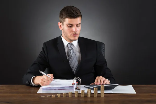 Geschäftsmann berechnet Steuer mit Münzen am Schreibtisch — Stockfoto