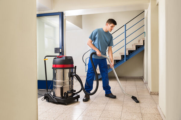 Male Worker Cleaning With Vacuum Cleaner