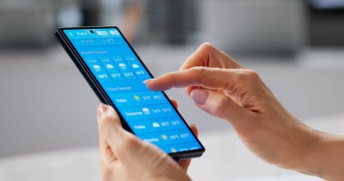 Monitoring Weather Forecast On Mobile Device In Contemporary Workspace