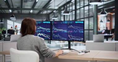 Genç Afrikalı Amerikalı Kadın ve Erkek, borsa grafiklerini analiz ediyor, muhtemelen finansal simsar olarak çalışıyorlar.