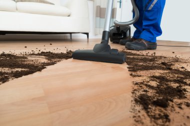 Erkek işçi yerleri elektrikli süpürgeyle temizliyor.