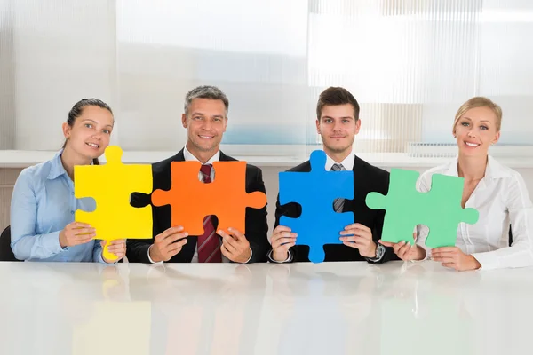 Imprenditori che tengono puzzle multicolori — Foto Stock