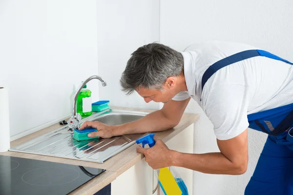 Dělník čištění dřezu v kuchyni — Stock fotografie