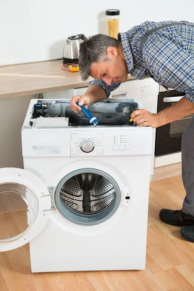 Klusjesman controleren wasmachine met zaklamp — Stockfoto