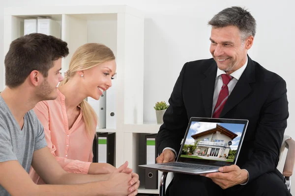 Makler zeigt Haus auf Laptop — Stockfoto