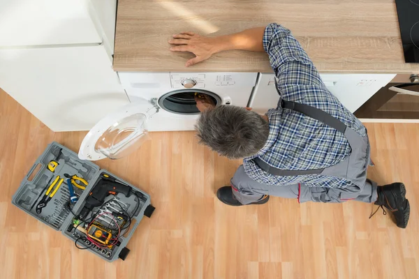 Handyman verificando máquina de lavar em casa — Fotografia de Stock