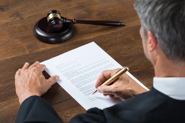 Juiz escrevendo sobre papel na sala de tribunal — Fotografia de Stock