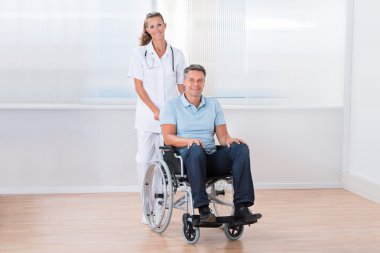 Doktor hasta tekerlekli sandalye üzerinde taşıyan