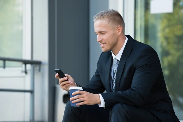 Üzletember keresi a mobiltelefon — Stock Fotó