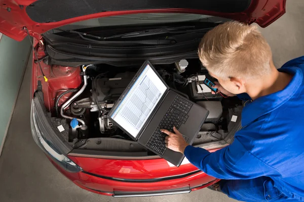 Mécanicien utilisant un ordinateur portable pour réparer la voiture — Photo