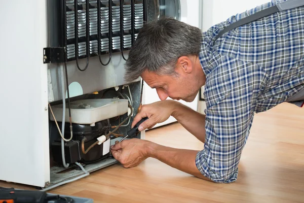 Serviceman Working On Fridge At Home — Stock Photo, Image