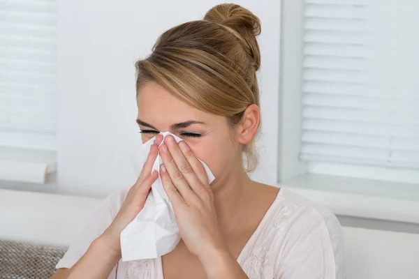 Женщина, сморкающая в нос, страдая от холода — стоковое фото