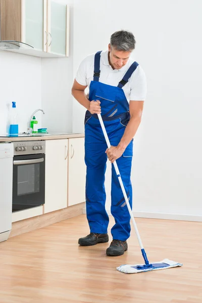 Dělník, vytírání podlahy v kuchyni doma — Stock fotografie