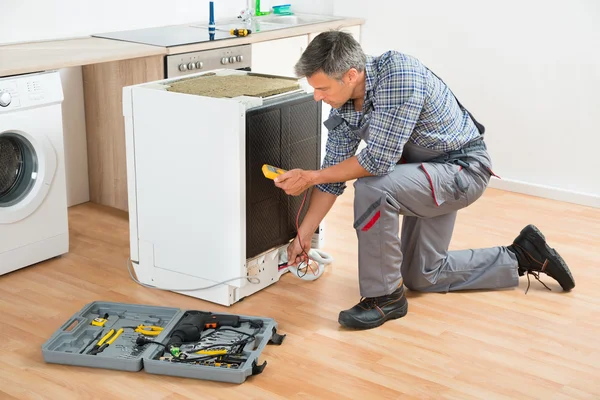 Teknikern kontrollera diskmaskin med Digital Multimeter — Stockfoto