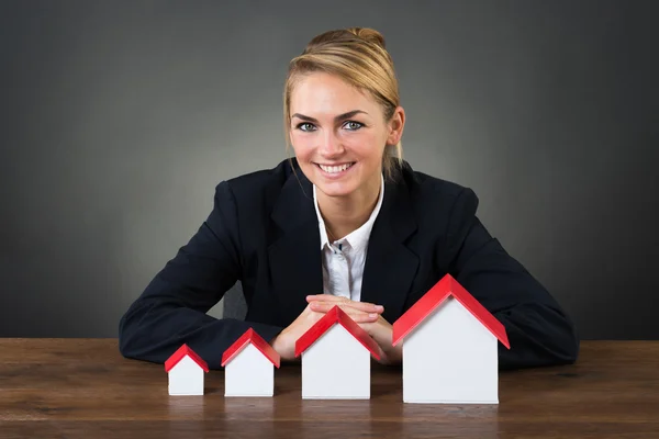 Glimlachende zakenvrouw met Model huizen — Stockfoto
