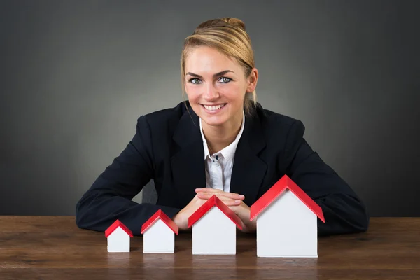 Femme d'affaires souriante avec des maisons modèles — Photo