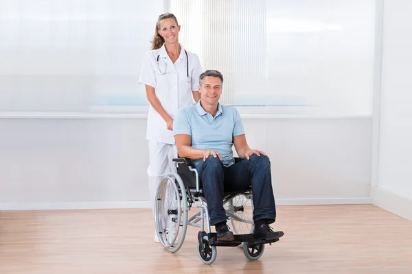 Arzt trägt Patient im Rollstuhl — Stockfoto