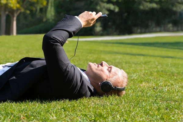 Uomo d'affari che gode di musica sulla cuffia — Foto Stock