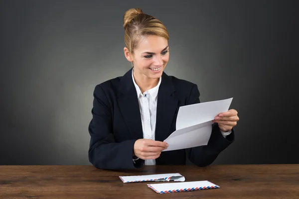 Junge Geschäftsfrau liest Brief am Schreibtisch — Stockfoto