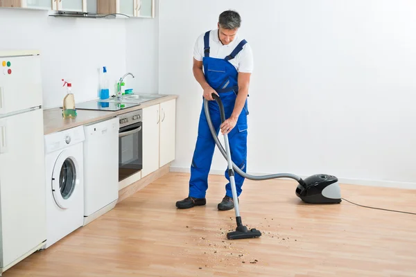 Εργαζόμενος καθαρίζοντας πάτωμα με ηλεκτρική σκούπα — Φωτογραφία Αρχείου