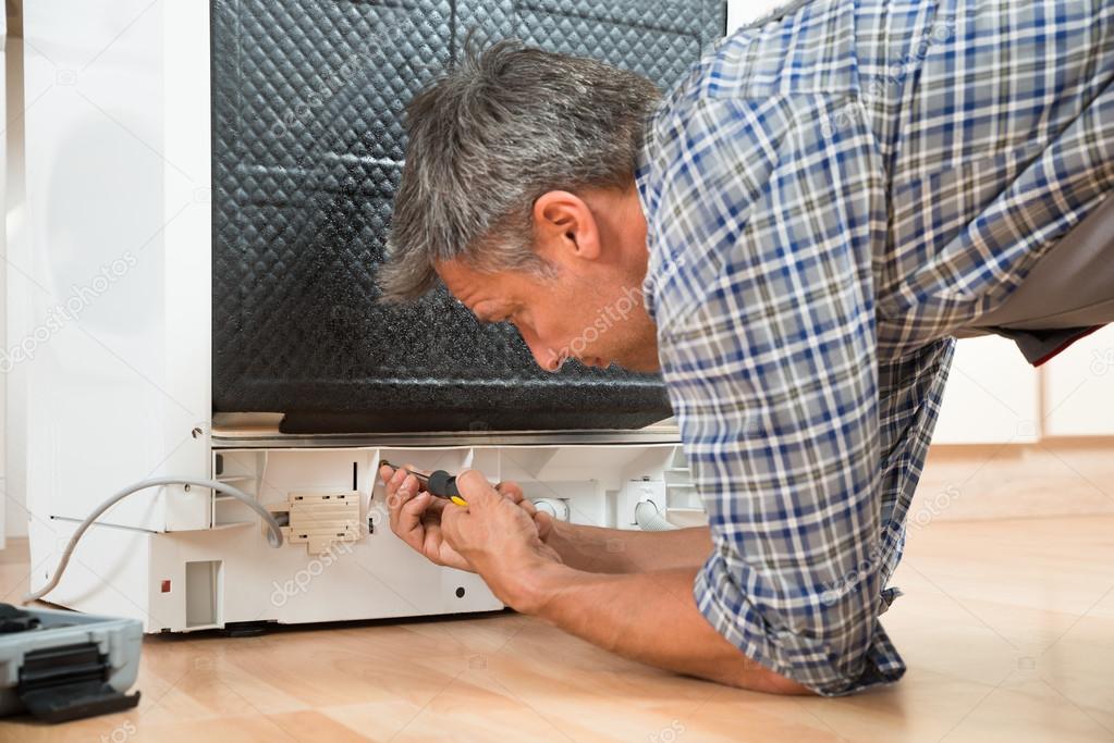 Repairman Repairing Dishwasher With Screwdriver
