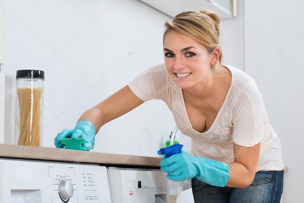 Woman Cleaning Kitchen Counter With Sponge