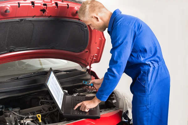 Mechanic laptop gebruikt terwijl het herstel van de auto — Stockfoto