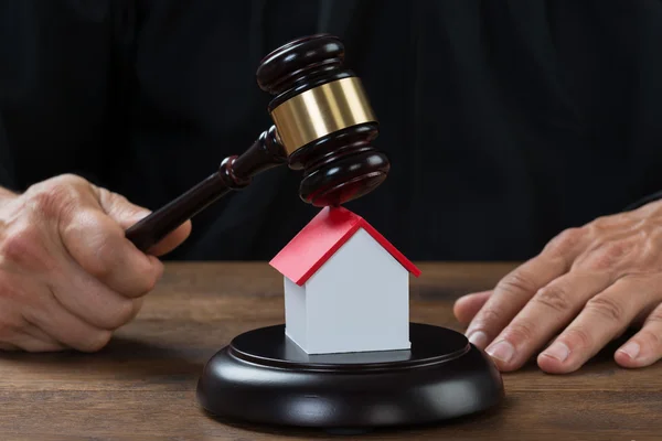 Juiz segurando Gavel na casa na mesa — Fotografia de Stock