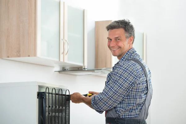 Glücklicher Heimwerker repariert Kühlschrank zu Hause — Stockfoto