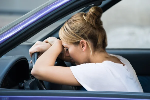 Kvinnan lutar sig på ratten i bilen — Stockfoto