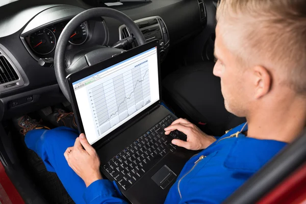 Mechaniker sitzt im Auto und benutzt Laptop — Stockfoto