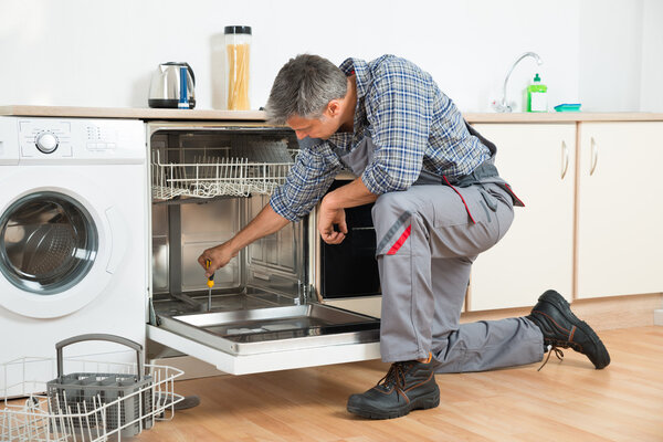 Ремонтник Посудомоечная машина с отверткой на кухне
