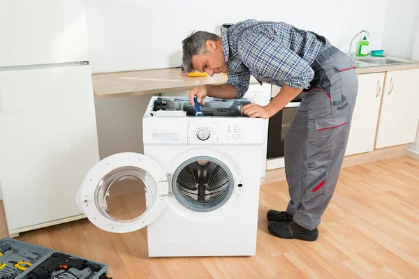 Handyman verificando máquina de lavar com lanterna — Fotografia de Stock