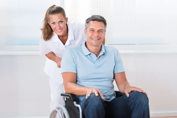 Doktor prowadzenie pacjenta na wózku inwalidzkim — Zdjęcie stockowe