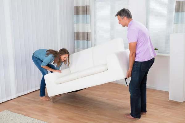 Paar versucht, eine Couch zu bewegen — Stockfoto