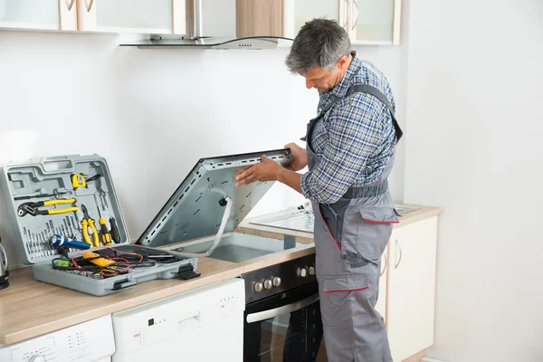 Reparador examinando estufa en la cocina — Foto de Stock