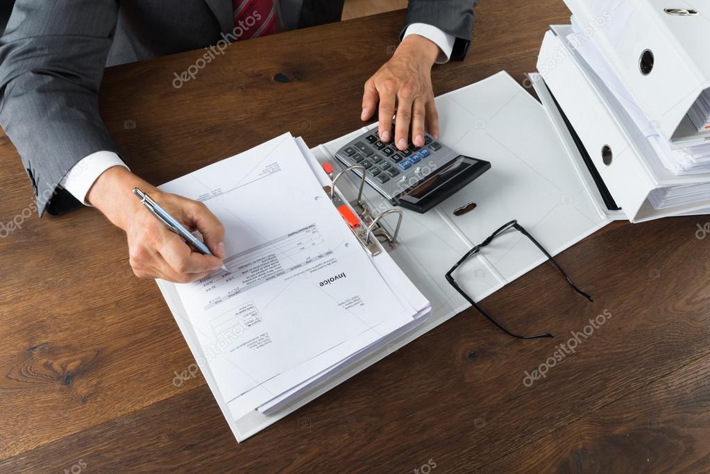 Businessman Checking Receipts At Desk