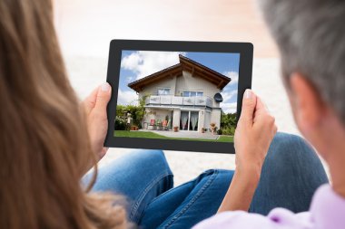 Looking At House Photo On Digital Tablet clipart