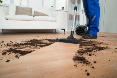 Yerleri elektrikli süpürgeyle temizliyorum.