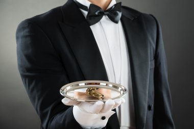 Midsection Of Waiter Holding Tray With Keys clipart