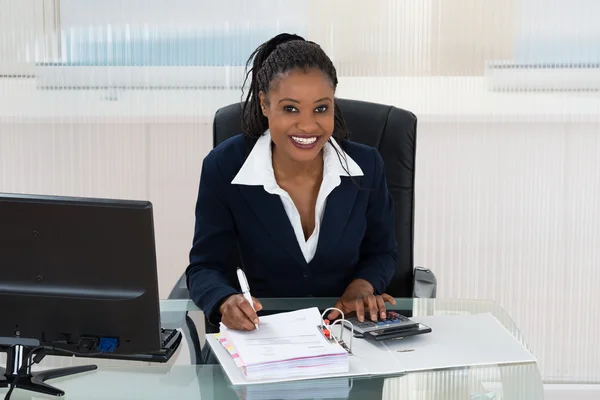 Mujer de negocios sonriente calculando facturas — Foto de Stock