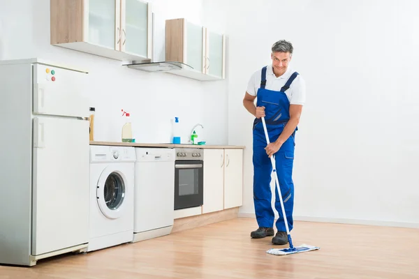 Εργαζόμενος Mopping το πάτωμα στην κουζίνα στο σπίτι — Φωτογραφία Αρχείου